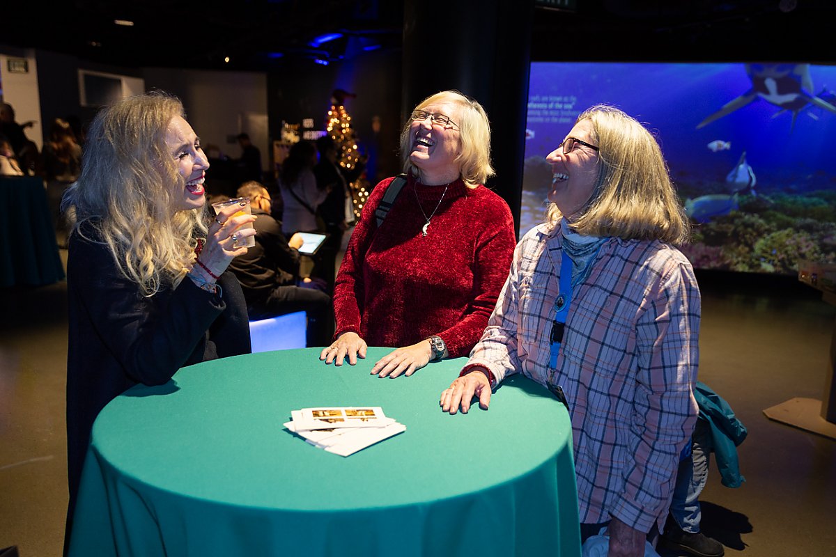 Three women at a cocktail table laughing