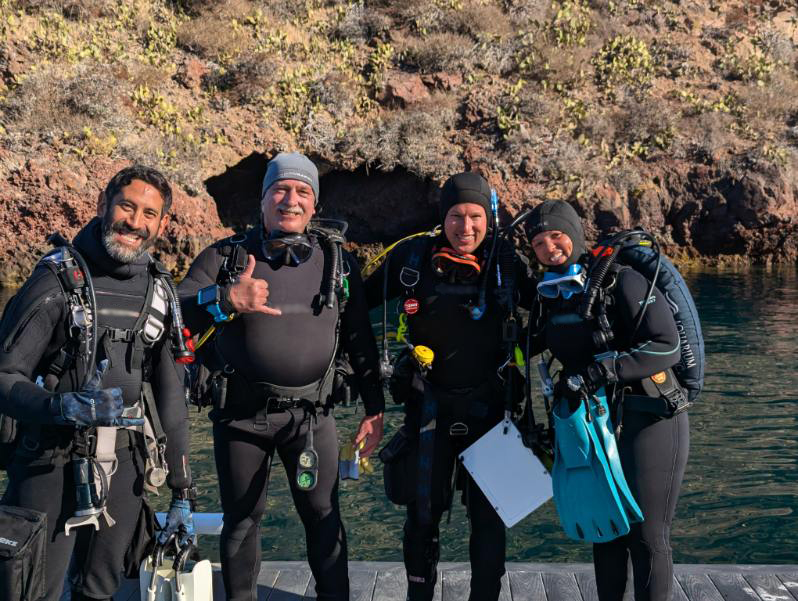 Four SCUBA divers pose side by side